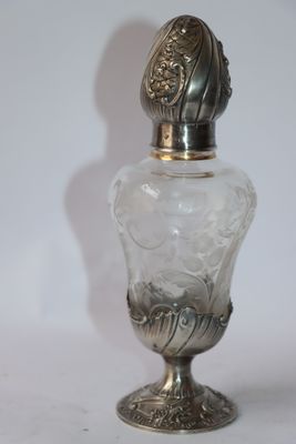 a glass bottle with a silver lid on a white surface