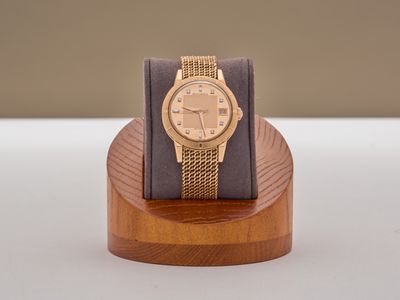 une montre en or posée sur un socle en bois, sur une table