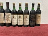 six bottles of wine are lined up on a red table cloth