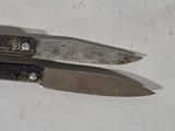 two knives that are laying side by side on a table