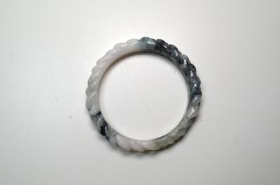 un gros plan d'un bracelet blanc et noir posé sur une surface blanche