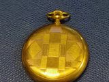 a gold pocket watch on a blue surface