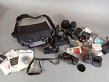a camera, a camera case, a camera lens, and other items laid out on a table