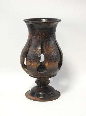 un vase brun posé sur une surface blanche