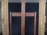 an old picture frame sitting on top of a chair next to a wooden easel