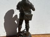 statue en bronze représentant un garçon avec un livre et un sac