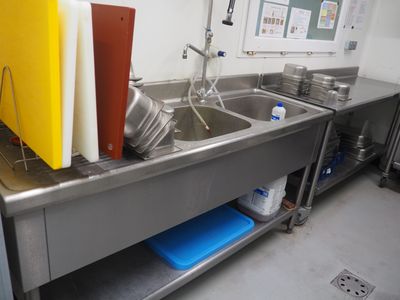 une cuisine équipée d'un évier et d'un plan de travail sur lequel sont posés des casseroles et des poêles