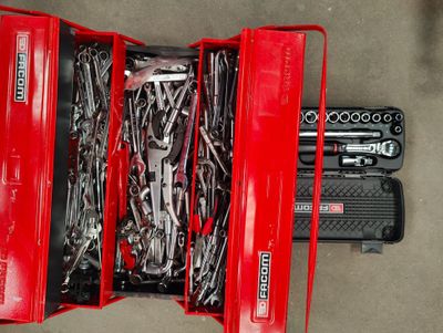 a red tool box filled with tools on the floor