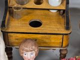 a small doll standing next to a table with flowers and a vase