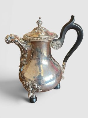 une cafetière ancienne en argent, dotée d'une poignée noire et d'une poignée noire