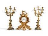 trois bougeoirs dorés et une horloge sur fond blanc