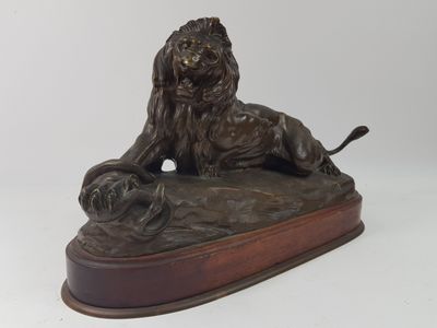 bronze statue of a lion on a wooden base with a white background