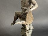 statue of a man sitting on a rock holding a glass of wine