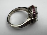 a close up of a silver ring with a red stone in it