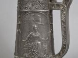 an antique pewed beer mug with an image of a woman and a bird on it
