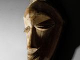 un masque en bois accroché à un mur dans l'obscurité