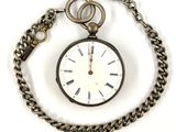 a pocket watch with a chain around it on a white surface