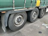 un semi-remorque vert avec un pneu crevé, garé sur le bord de la route