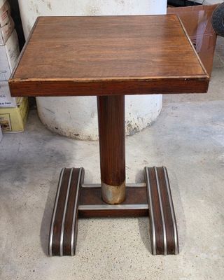 une petite table en bois avec un piètement en métal, posée sur un sol en béton