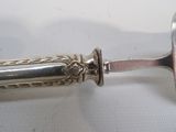 a silver spoon with a handle on a white surface