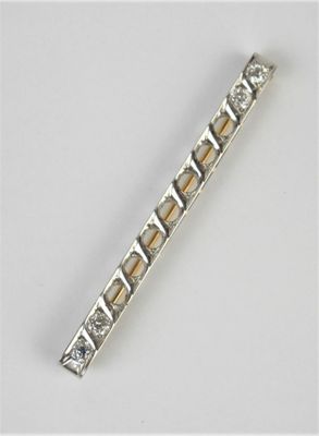 un gros plan sur une broche en forme de barre, en argent et en or