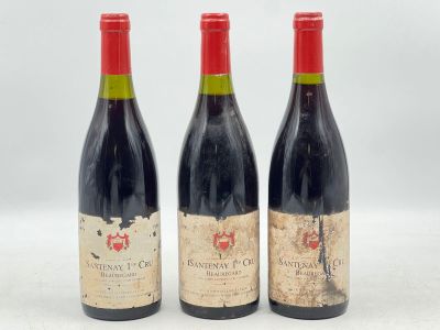trois bouteilles de vin rouge sont alignées sur une surface blanche