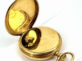a gold pocket watch sitting on a white surface