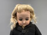 a doll with blonde hair and a black coat