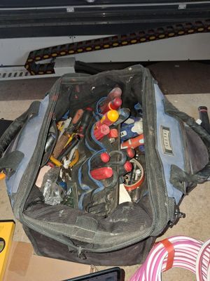 un sac rempli d'outils posé par terre à côté d'un ordinateur portable