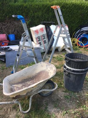 a wheelbarrow, a bucket, a ladder, a bucket, and a bucket of dirt in a yard