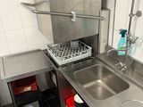 a kitchen with a sink, stove, and trash can in it