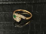 gros plan d'une bague en or avec une pierre verte