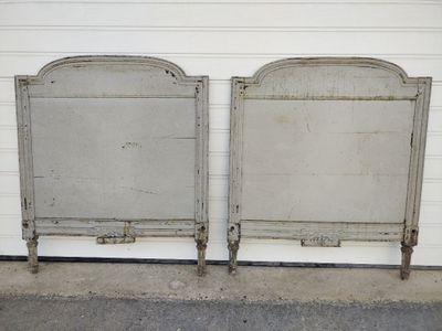 two metal beds sitting next to each other in front of a white wall
