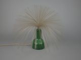 un vase vert dans lequel se trouve une plume blanche