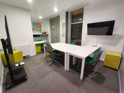 une table blanche avec des chaises vertes et une télévision accrochée au mur