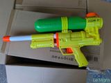 a yellow and green water gun on top of a cardboard box