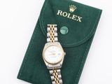 a close up of a rolex watch on a green case