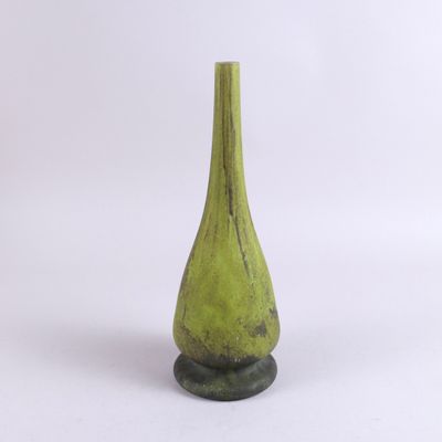 un vase vert posé sur une surface blanche