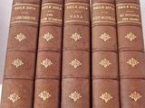 six old books are lined up on a white surface