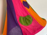 purple, orange, and green dress hanging on a white wall