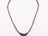a necklace with purple beads and a silver clasp on a white background