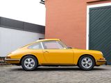 yellow porsche 911 parked in front of a building with a garage behind it