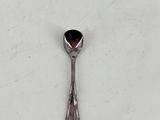 a spoon with a black stone on it on a white surface