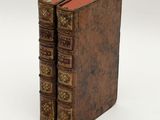 two old books sitting on top of each other on a white surface