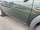 un gros plan d'une voiture verte avec une clôture en arrière-plan