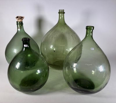 trois vases en verre vert posés sur une surface blanche