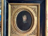 painting of a woman in a black dress in a gold frame on a table