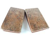two old books sitting on a white surface
