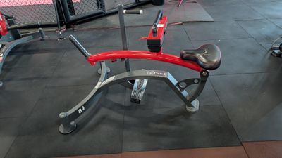 a red and silver bench in a gym with other gym equipment