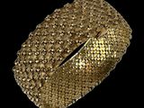 gros plan d'un bracelet en or sur fond noir